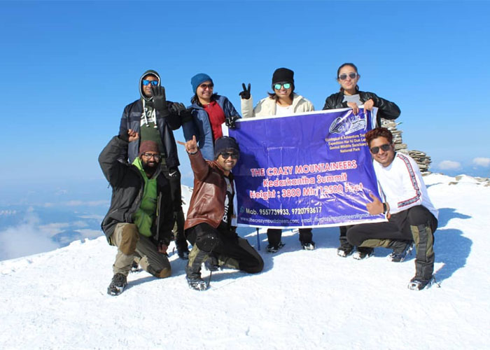 Trekkers Displaying The Crazy Mountainners Banner at Kedarkantha Summit